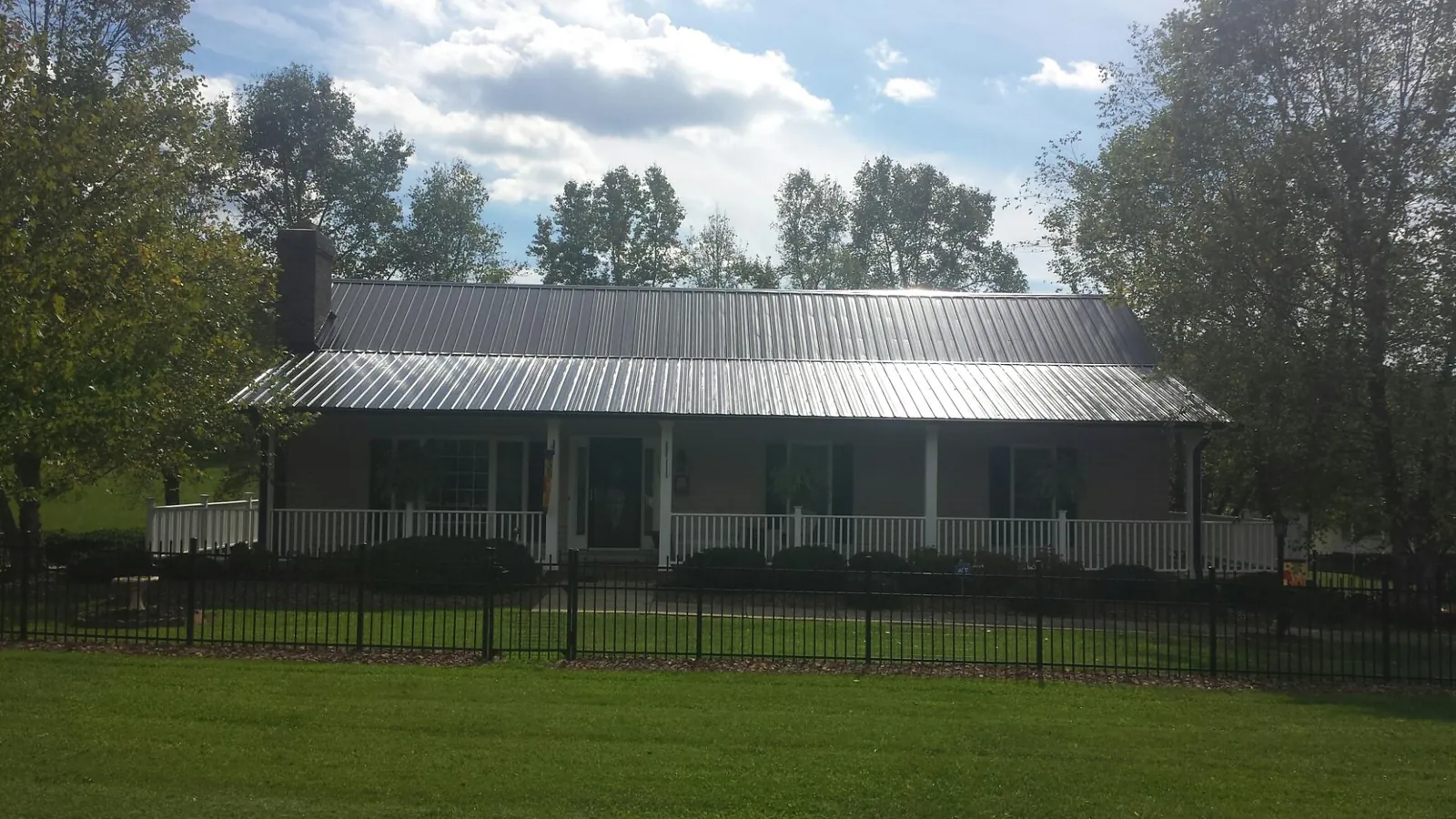 Gray metal roof on a brick ranch with a full width front porch — Gutter Guard Installation work by our crew in Herreid