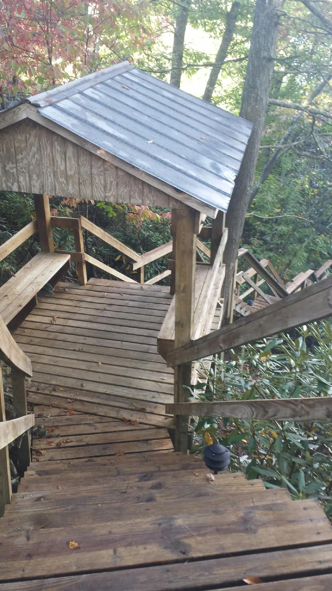 Metal roofed shelter over wooden steps on a wooded walkway — Skylight Repair & Installation work by our crew in Herreid