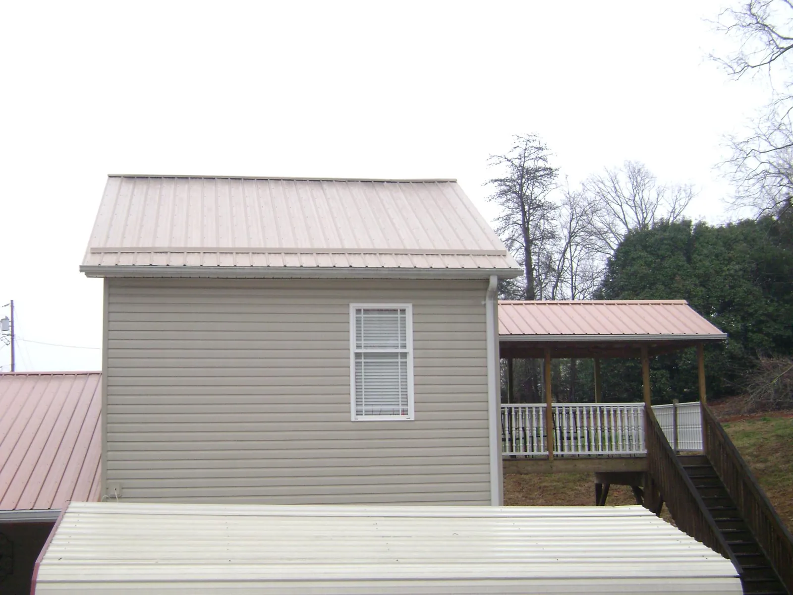 Tan metal roofs on a two story addition and attached porch, from a Roof Replacement job in Herreid