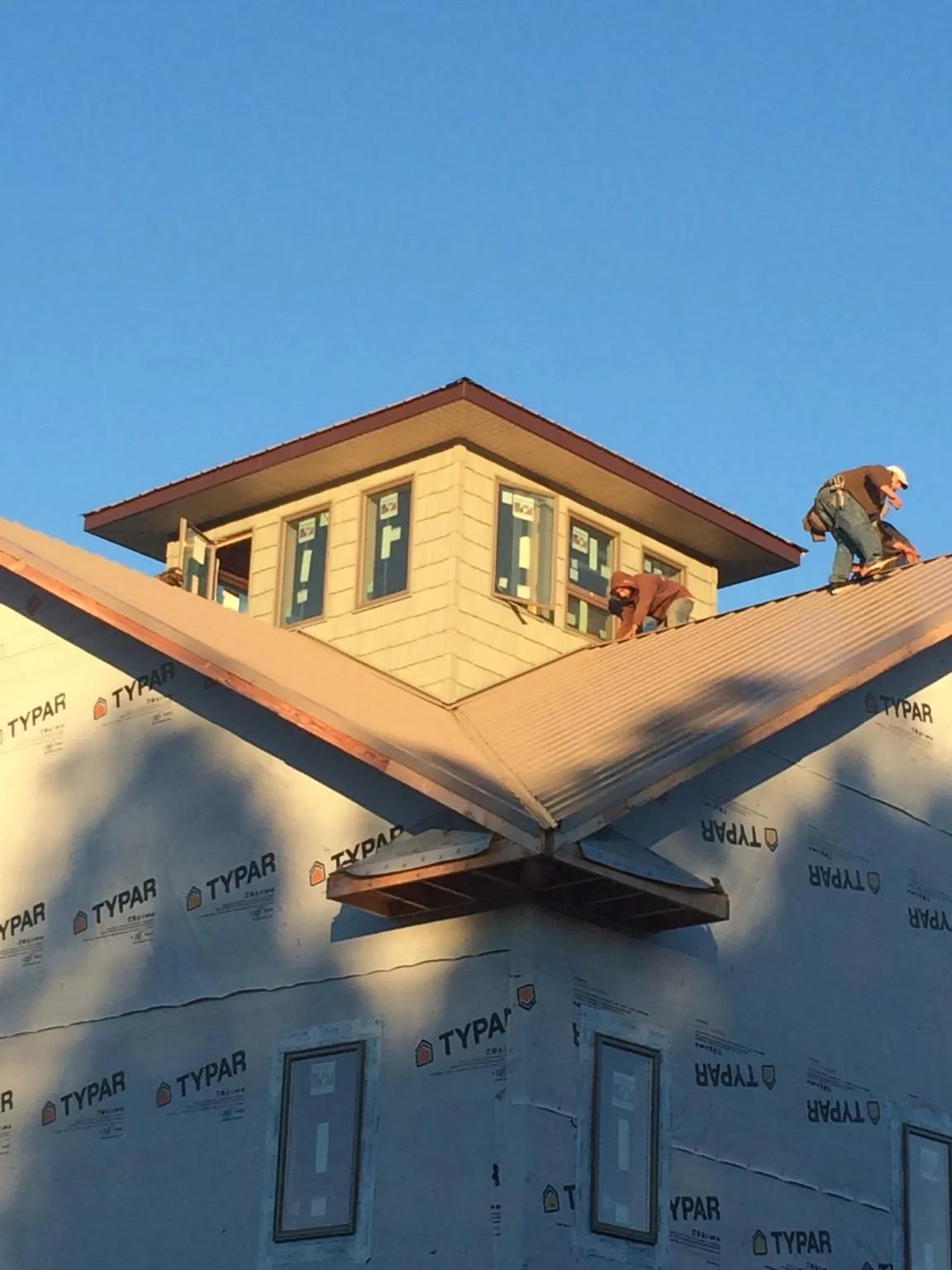 Roofers working around a rooftop cupola on a new metal roof at sunset — Roof Waterproofing in Herreid by Roofing Brothers